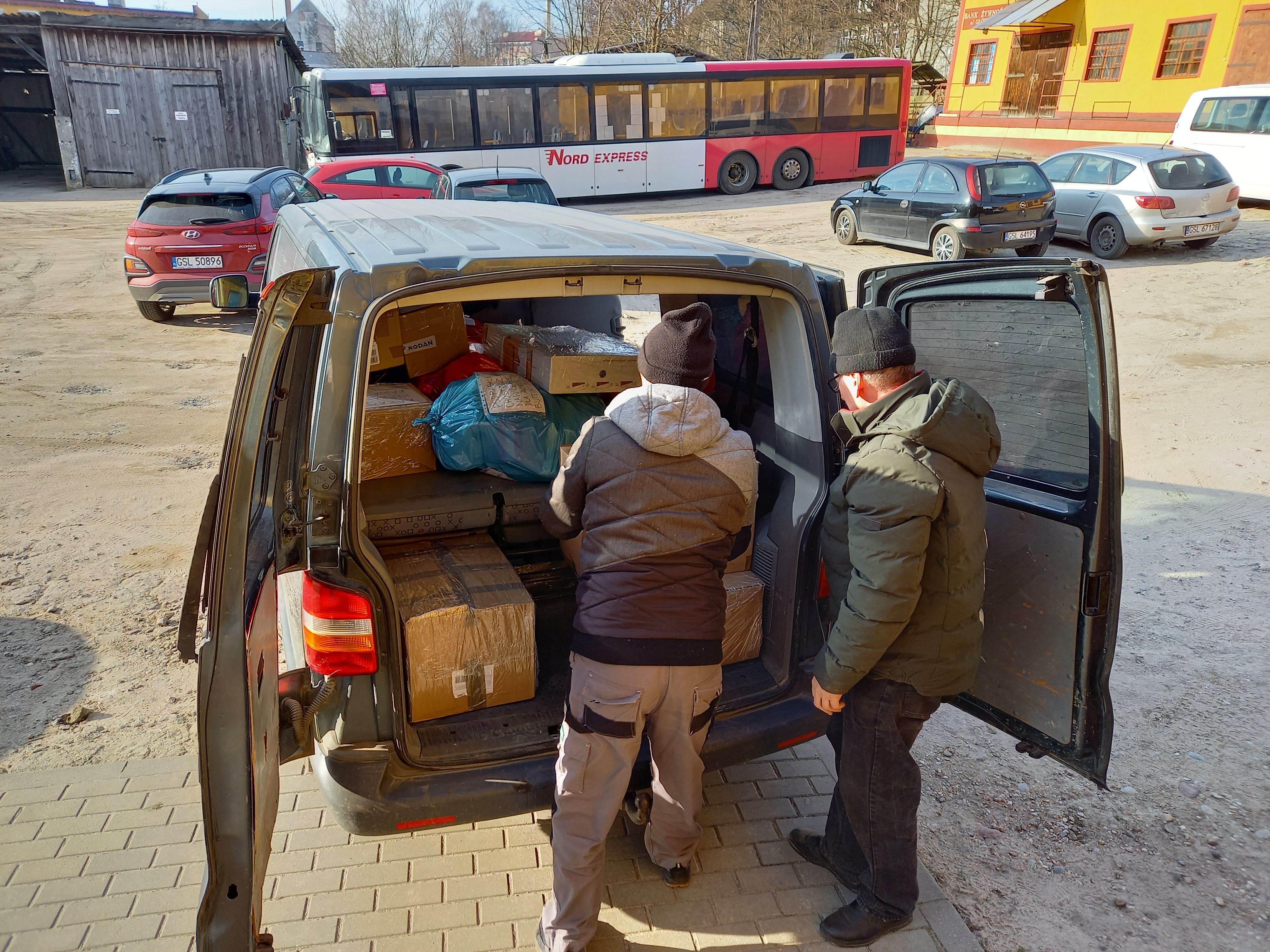 Dwóch panów pakujących do busa paczki