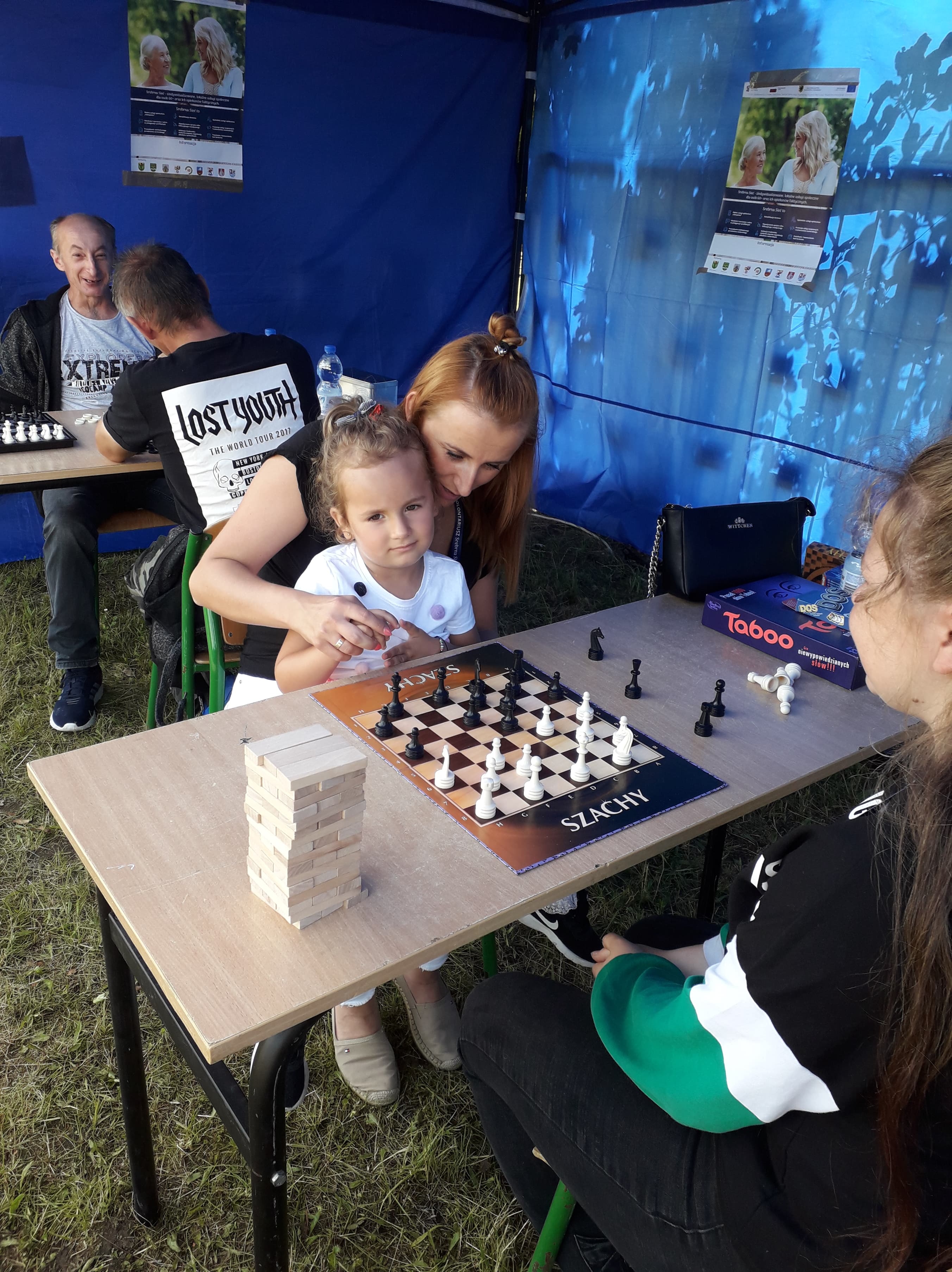 Uczestnicy Główczyckiego Festiwalu Lata grający w gry planszowe pod namiotem promującym projekt Srebrna Sieć.
