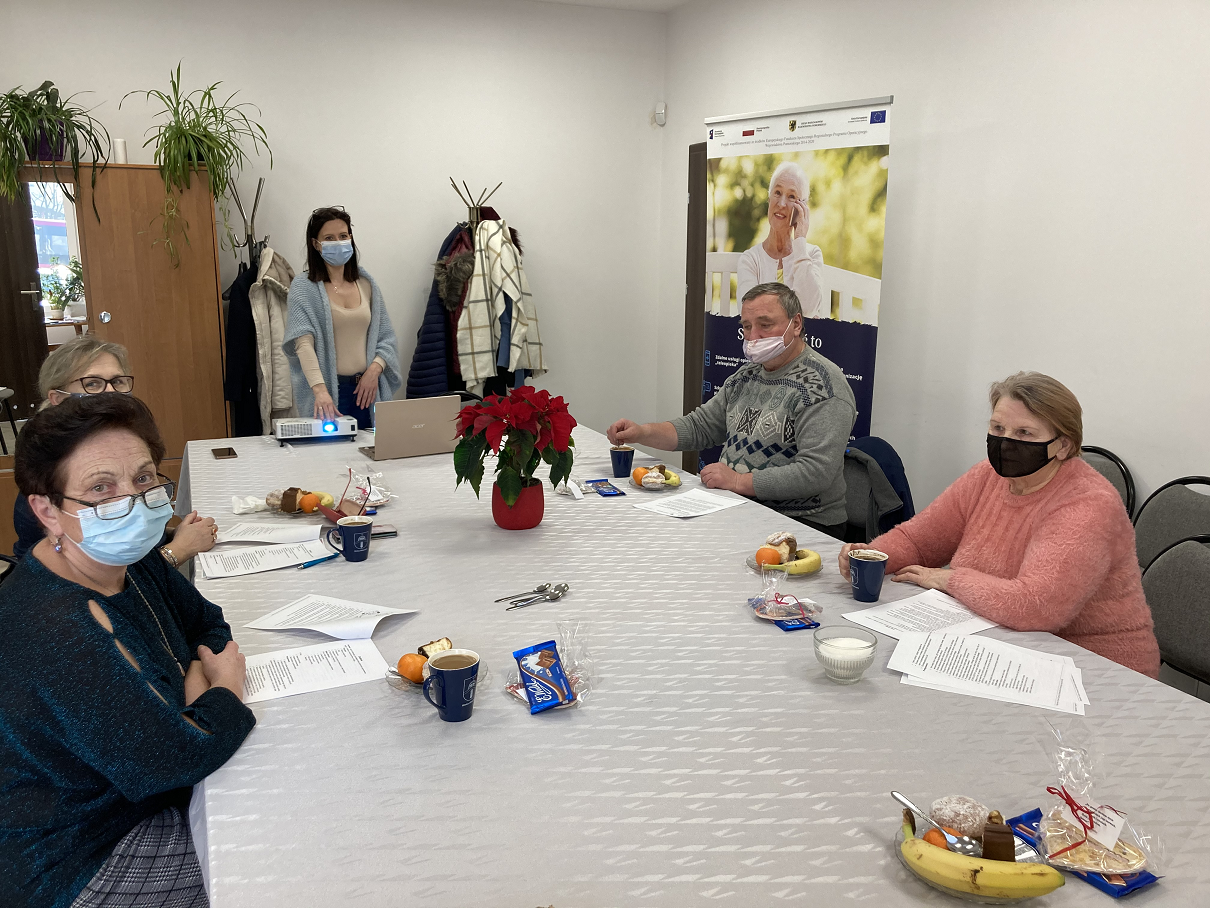 Opiekunowie skupieni wokół stołu w towarzystwie trenerki