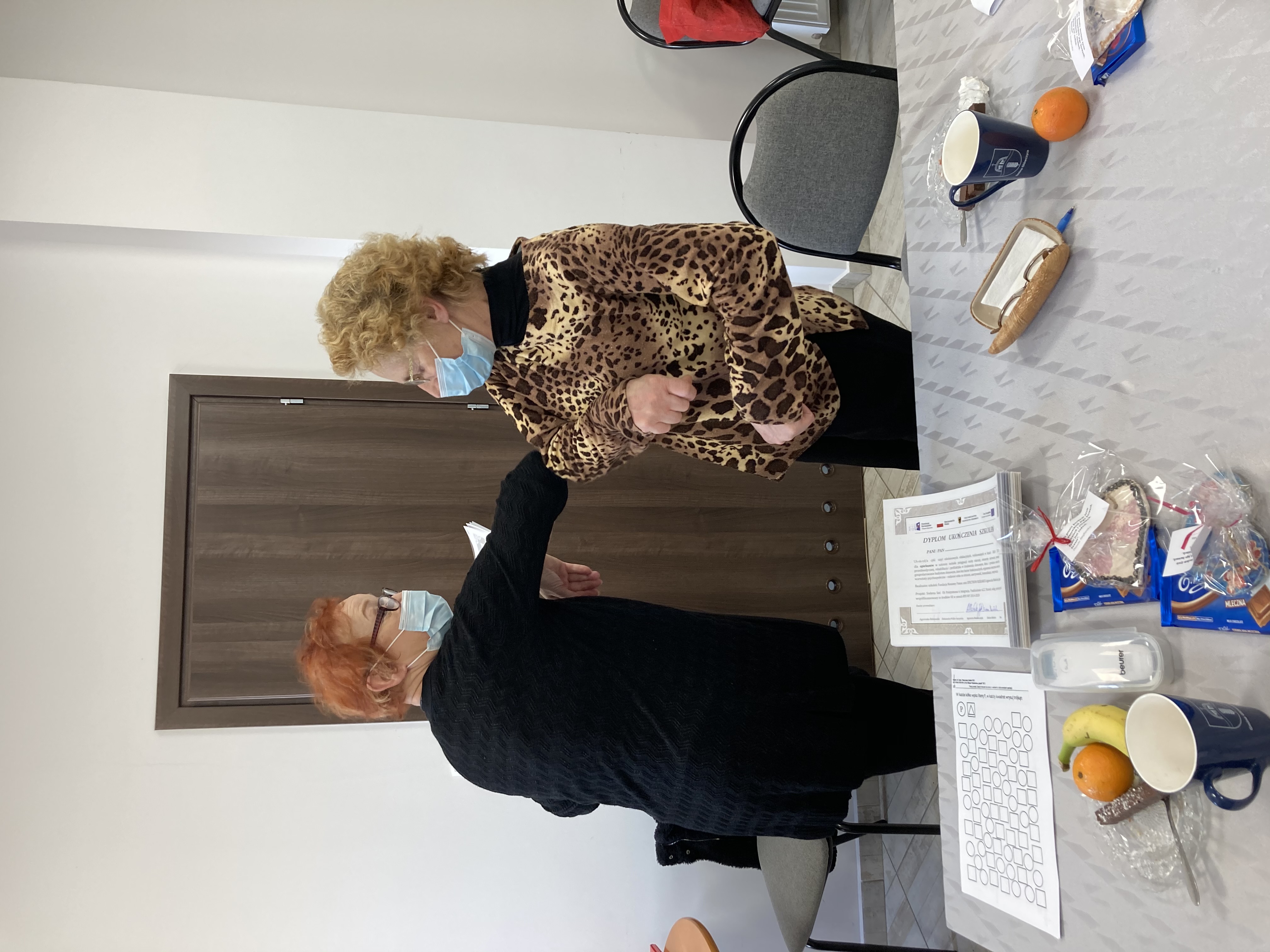 Powitanie łokciem między kierownikiem OPS a seniorką - jedną z uczestniczek szkolenia.