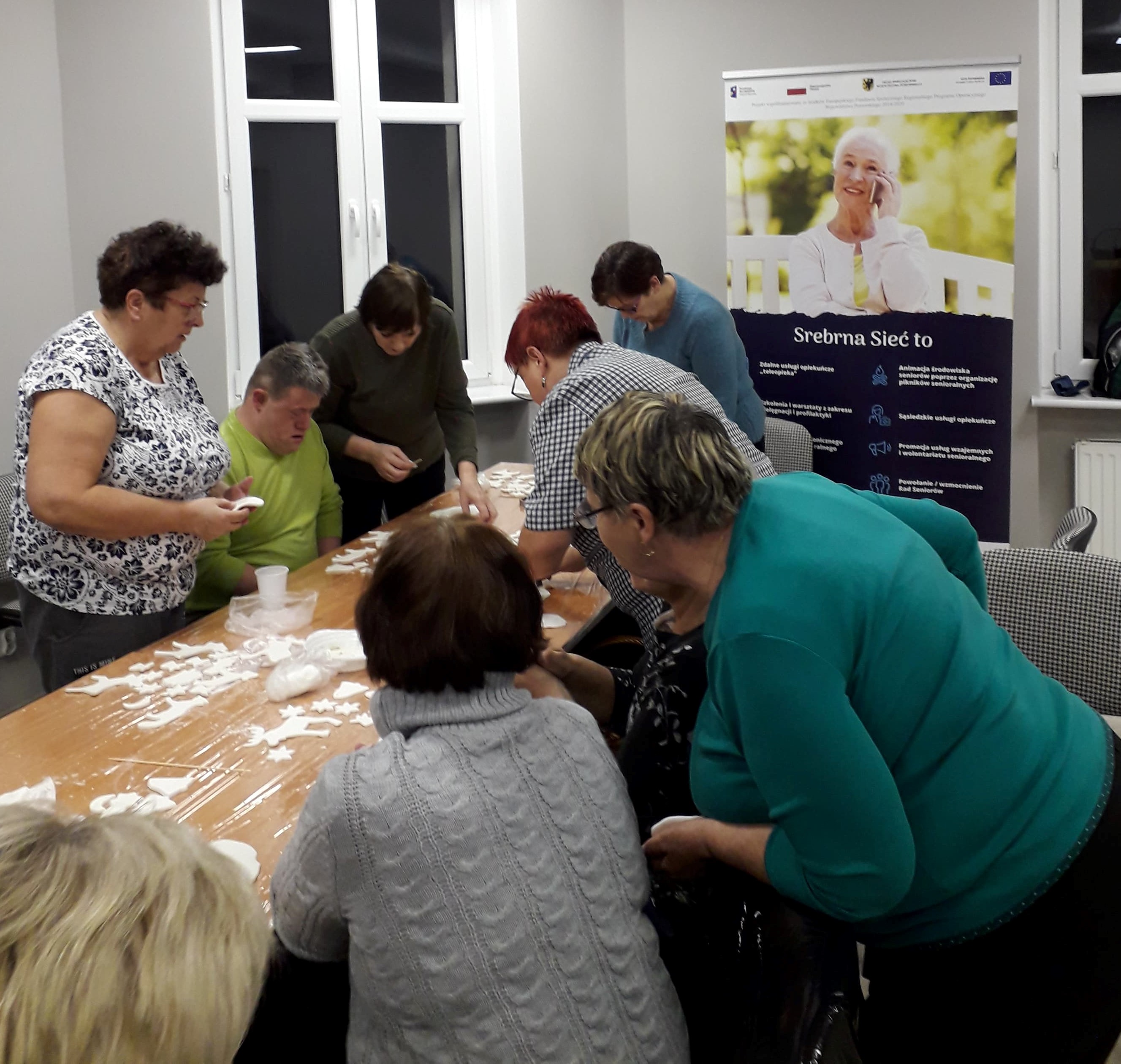 Uczestnicy warsztatów przy stole podczas prac nad ozdobami świątecznymi.