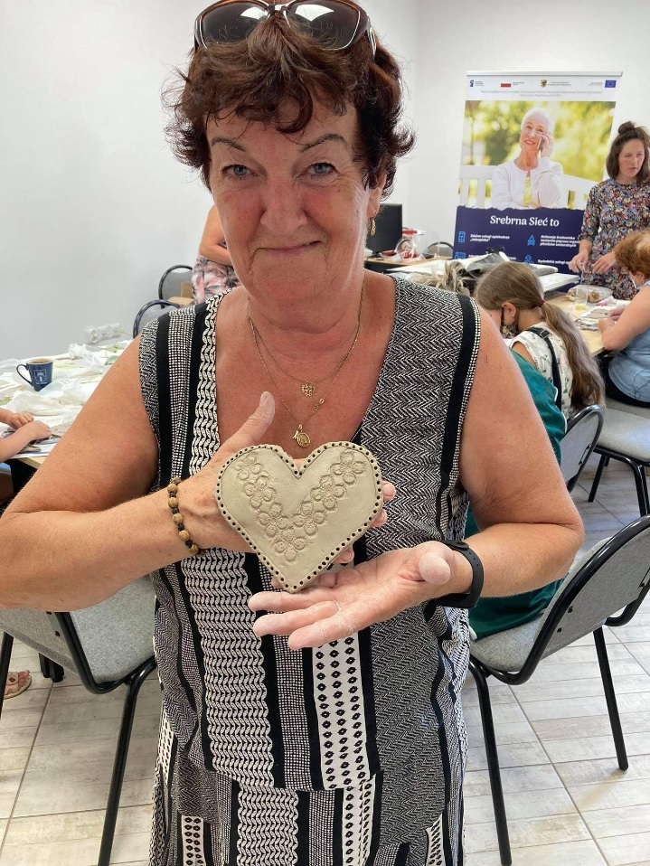 Pani z Rady Seniorów prezentująca wykonane z gliny serce.