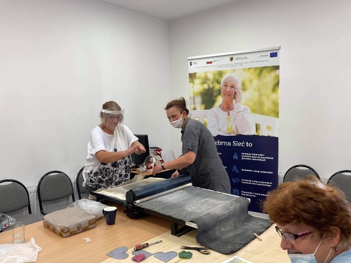 Uczestnicy warsztatów podczas pracy przy sprzęcie do obróbki gliny.