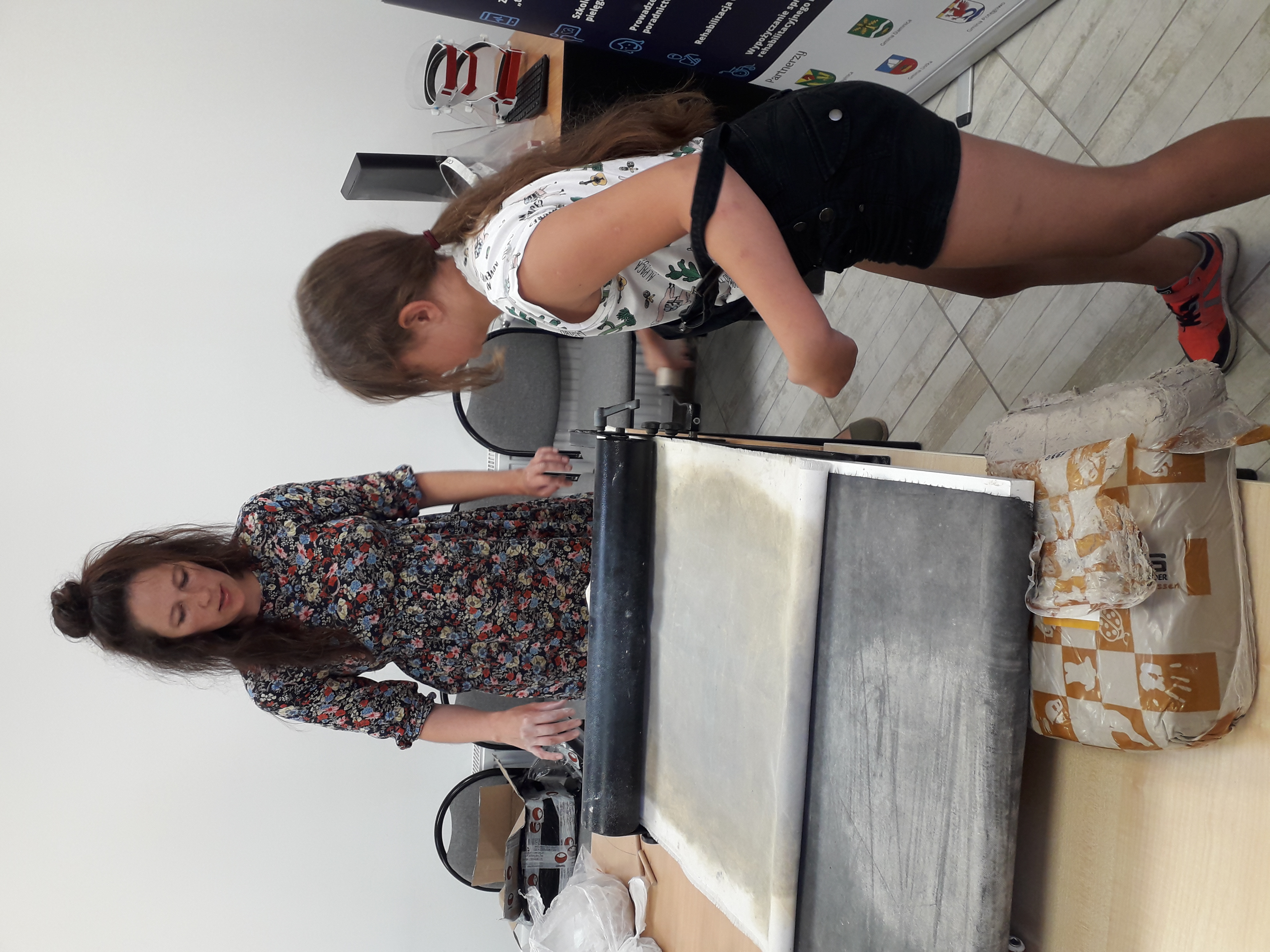 Uczestnicy warsztatów podczas pracy przy sprzęcie do obróbki gliny.