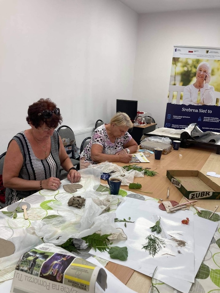 Uczestnicy warsztatów tworzacy wzory na sercach z gliny.