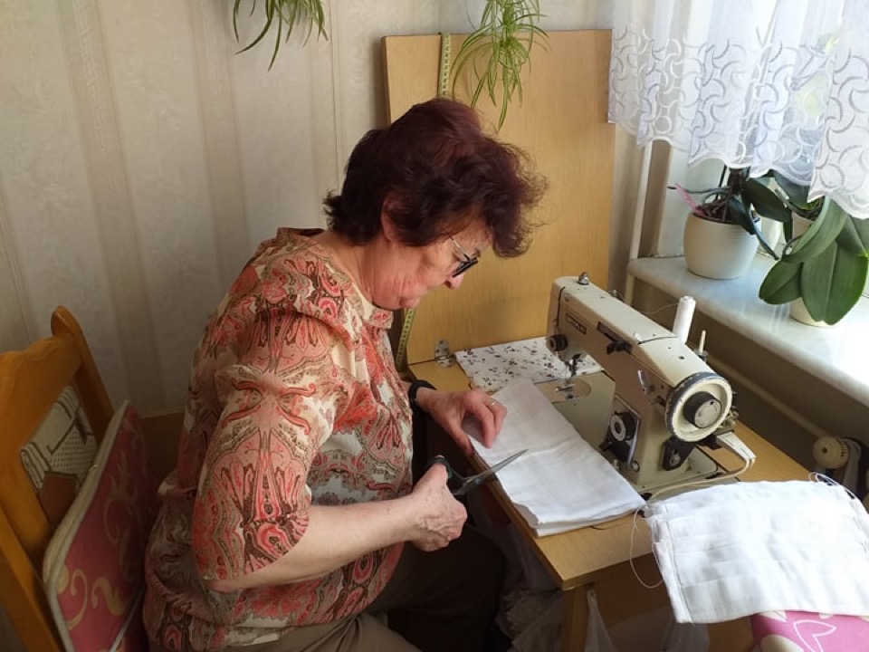 Pani wycinająca materiał na maseczki przy maszynie do szycia,