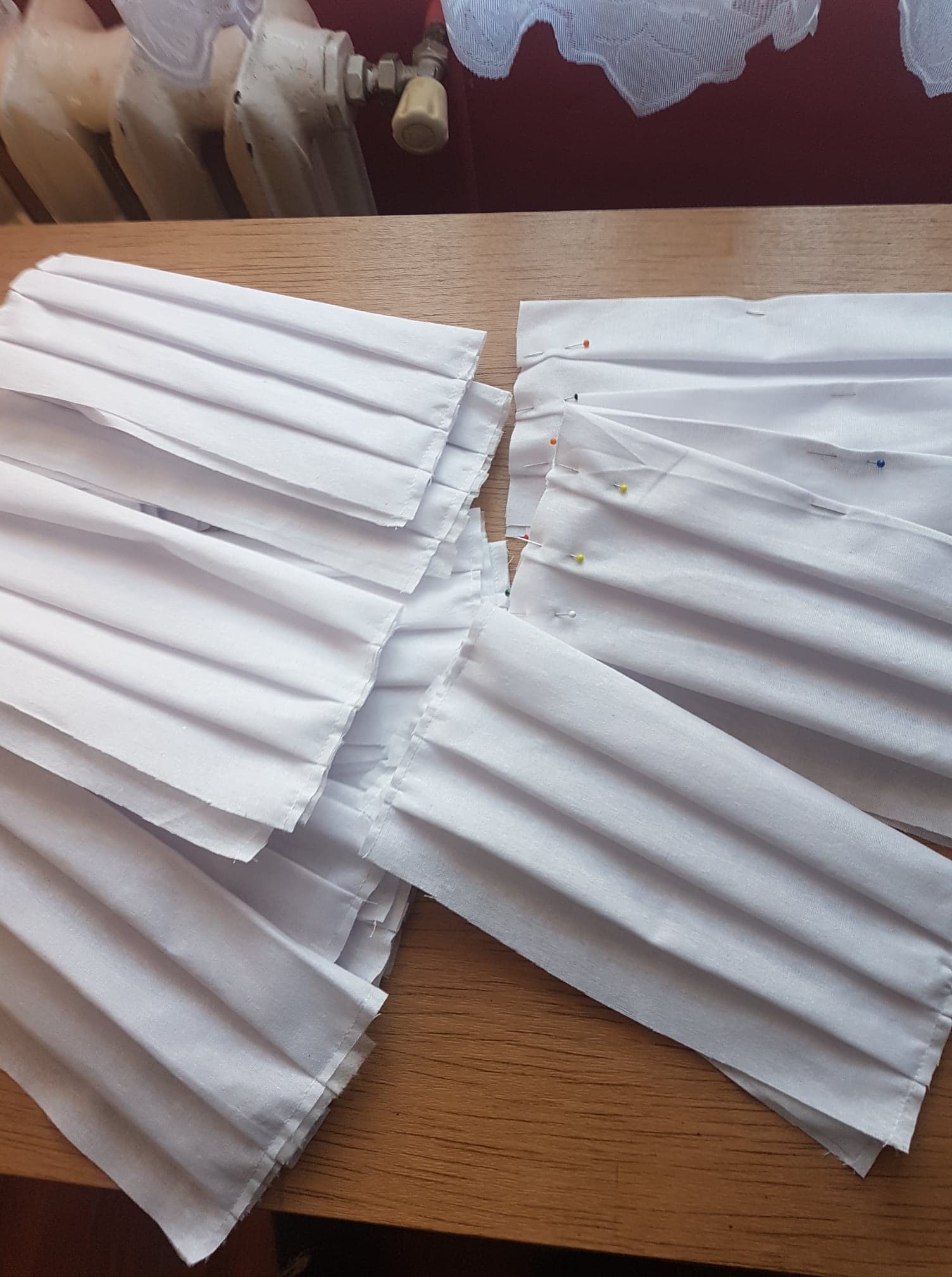 Materiał na maseczki ochronne ułożony do szycia, spięty szpilkami.