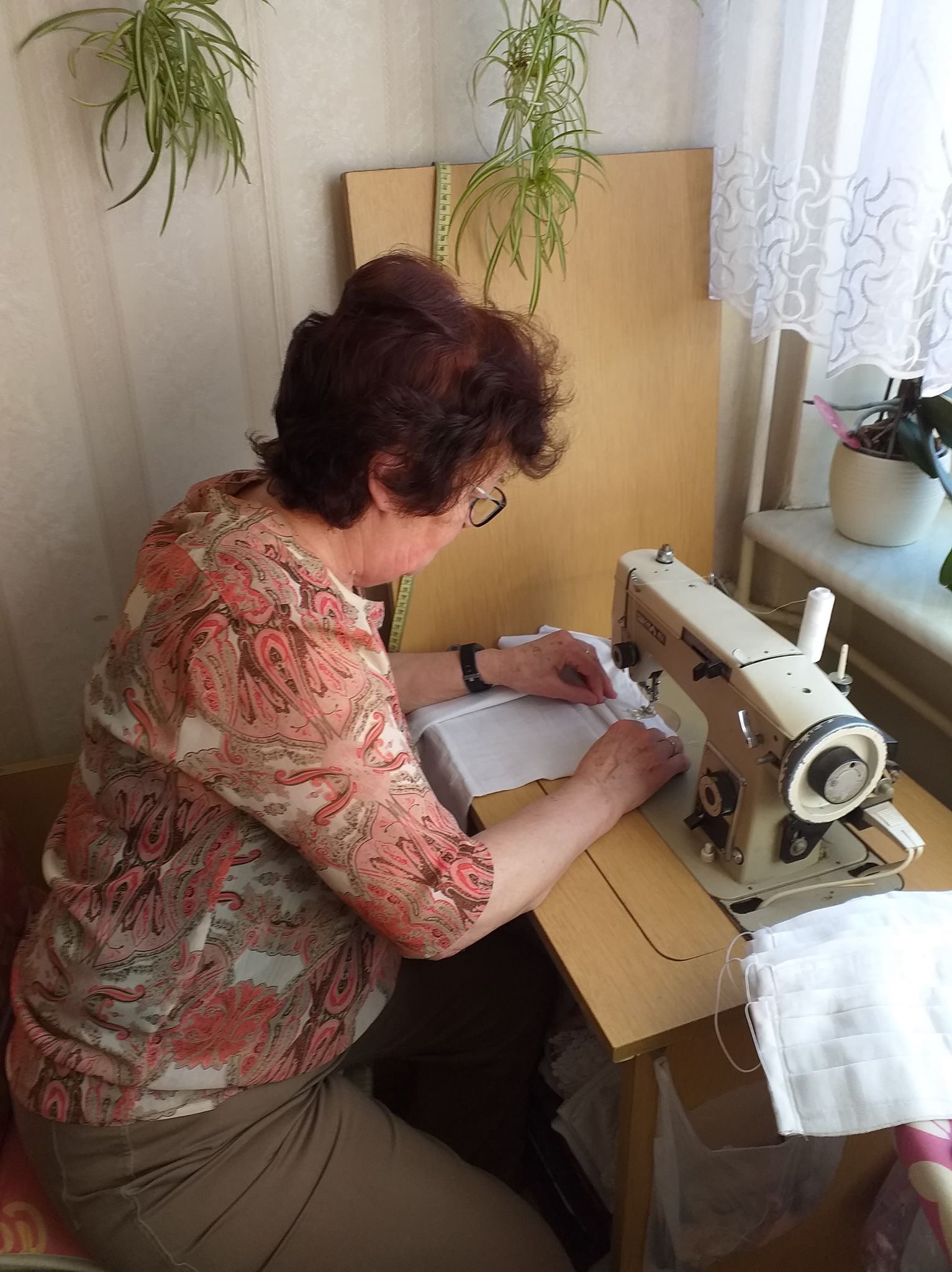 Pania szyjąca maseczki ochronne na maszynie do szycia.