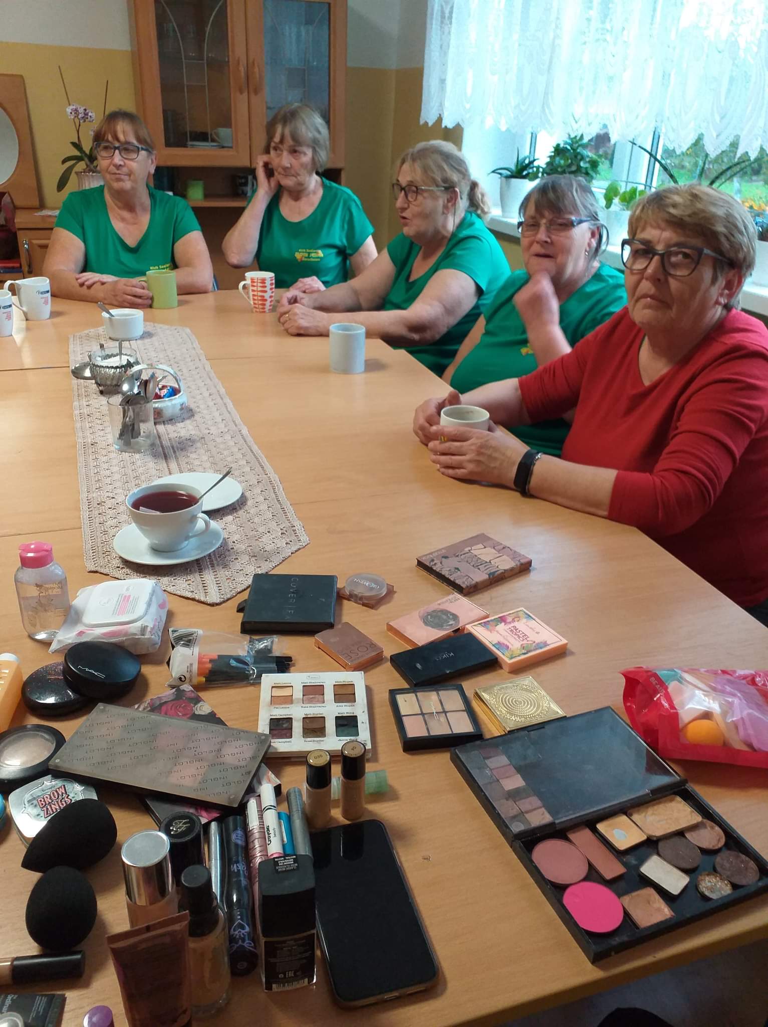 Uczestnicy Klubu Seniora siedżacy woków stołu i przysłuchujący się osobie prowadzącej warsztaty