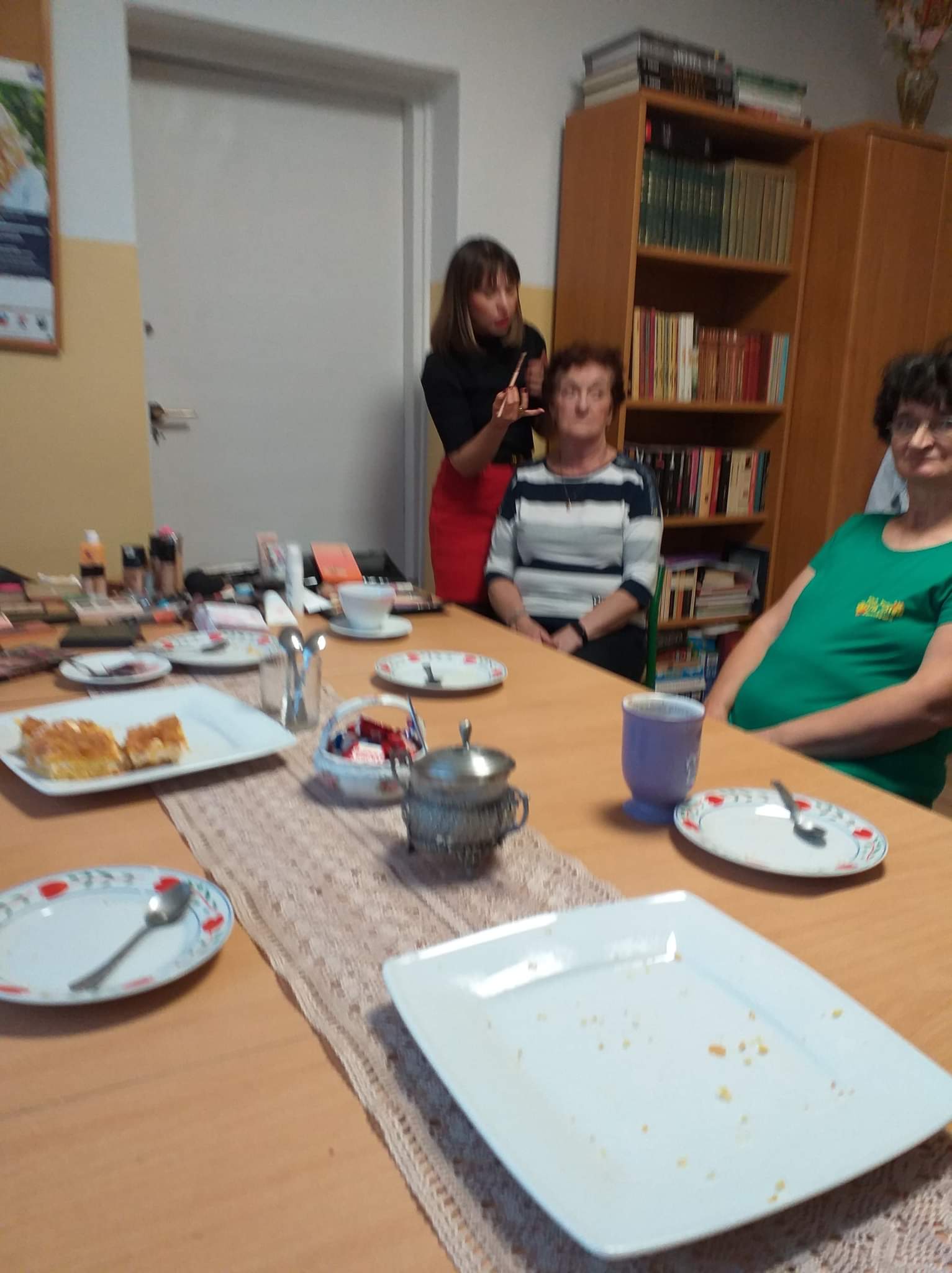 Instruktorka  malująca jedną ze zgromadzonych seniorek