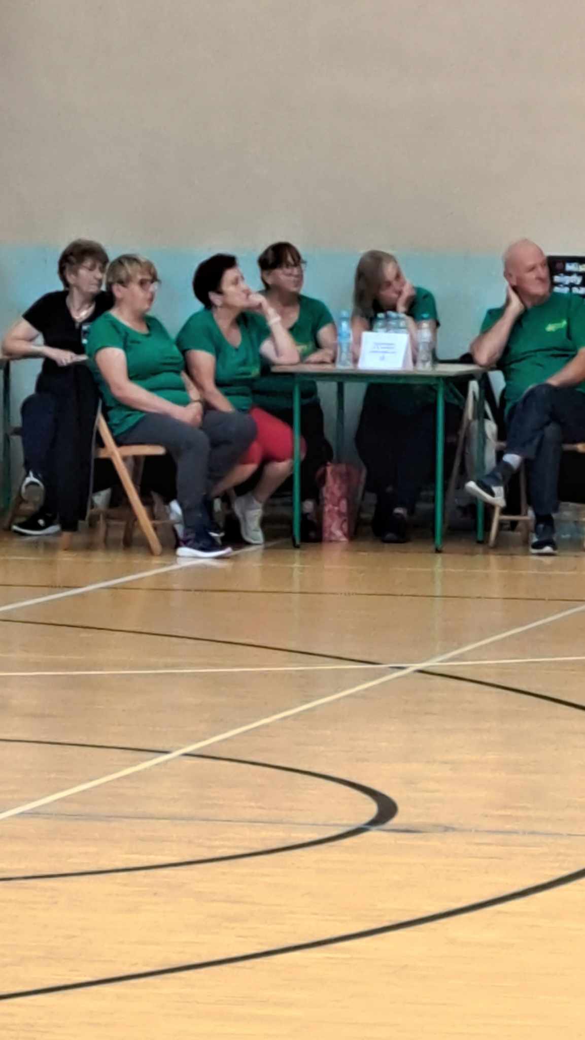 Seniorzy siedzący przy swoim stanowisku, oglądając inne zespoły